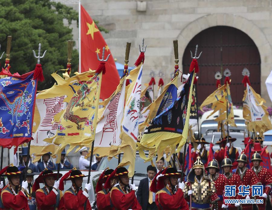 7月3日，韓國總統(tǒng)樸槿惠在青瓦臺總統(tǒng)府舉行隆重儀式，歡迎中國國家主席習近平對韓國進行國事訪問。這是習近平的車隊在身著民族服裝的韓國禮儀隊伍引導下駛?cè)肭嗤吲_。新華社記者丁林攝  