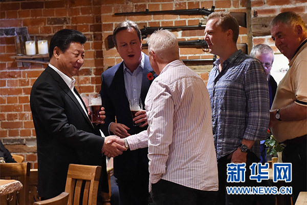 這是習近平與卡梅倫飲啤酒，并同當?shù)孛癖娊徽?。新華社記者 饒愛民 攝